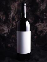 Elegant red wine bottle on dark textured background photo