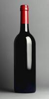 Dark glass wine bottle with a red cap on neutral background photo