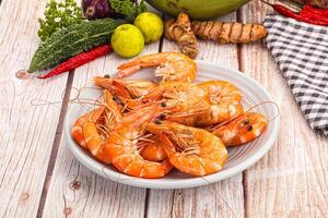 A bowl of shrimp on a table next to a bowl of vegetables photo