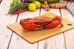 A crab on a cutting board with other vegetables photo