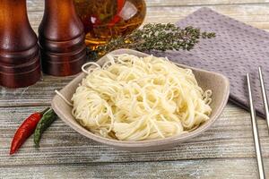 A bowl of noodles with chopsticks and a bottle of soy sauce photo