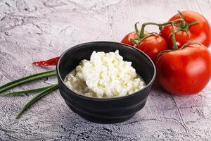Cottage cheese in a bowl with tomatoes and herbs photo