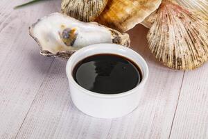 A cup of coffee and an oyster on a wooden table photo