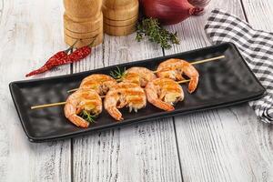 Grilled shrimp on skewers on a black plate photo