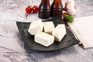 A black plate with four pieces of cheese on it photo