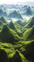 Lush green landscape with mountains and mist at sunrise photo