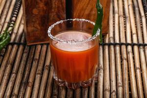 A drink with a green garnish sitting on a bamboo mat photo