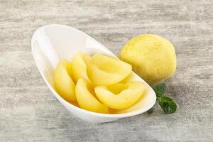 A white bowl with a lemon and a few pieces of fruit photo