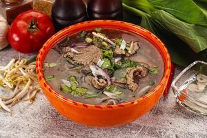 A bowl of soup with meat and vegetables on a table photo