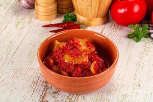 A bowl of tomato sauce with a knife and a tomato photo