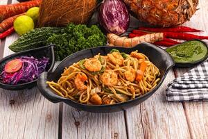 A table with a bowl of noodles, vegetables and a pineapple photo