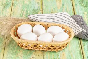 White eggs in a basket on a wooden table photo