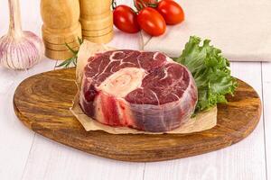 A piece of meat on a cutting board with vegetables photo