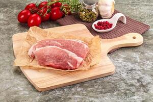 Raw meat on a cutting board with spices and tomatoes photo