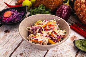 A bowl of salad with vegetables and pineapple on a wooden table photo