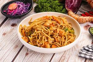 A bowl of noodles and vegetables on a table photo