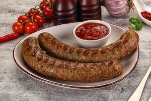 Two sausages on a plate with ketchup and tomatoes photo