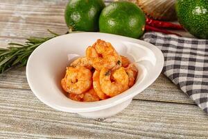 A bowl of shrimp on a table next to some other food photo