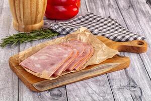 Sliced ham on a wooden cutting board with a glass of beer photo