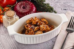 A white bowl with meat and vegetables on a table photo