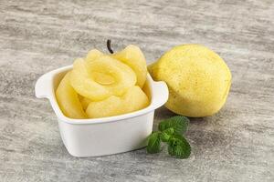 A white cup with a slice of lemon and a small bowl with a slice of pear photo
