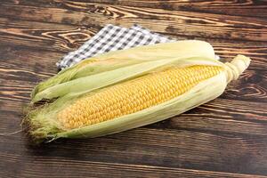 A corn on the cob with a napkin on a wooden table photo