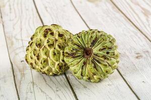 A pair of green fruit on a wooden table photo