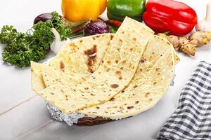 A basket of tortillas on a table with vegetables and other food photo