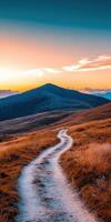 Winding dirt path leading to a mountain during sunset photo