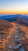 A trail leads up to a mountain at sunset photo