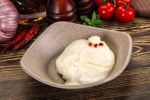 A bowl of ice cream sitting on a table next to a bowl of tomatoes and garlic photo