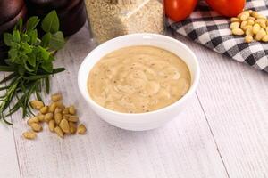 A bowl of peanut butter sauce on a wooden table photo