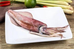 A squid on a plate with other vegetables and a knife photo