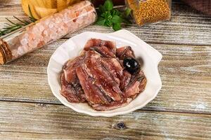 A bowl of meat and spices on a wooden table photo