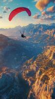 Paraglider flying over the mountains at sunset photo