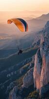 Paraglider flying over mountains at sunset photo