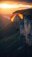 Paraglider flying over the mountains at sunset photo