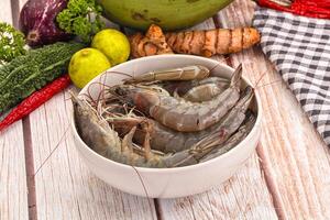 A bowl of shrimp sitting on a table next to other vegetables photo