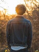 Young man enjoying a sunset in nature by the forest photo