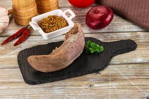 A piece of meat on a black board with spices and other ingredients photo