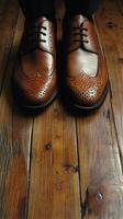 A man's feet in brown shoes on a wooden floor photo