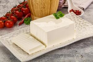 A square of cheese on a plate with tomatoes and a glass of milk photo