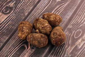 A pile of brown potatoes on a wooden table photo