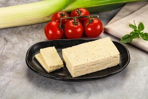 A plate with a piece of tofu and some vegetables photo