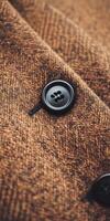 Close-up view of a black button on brown textured fabric photo
