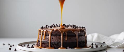 A chocolate cake with caramel sauce being poured over it photo