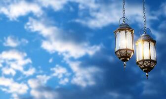 Two ornate lanterns hang against a blue sky with soft clouds. photo