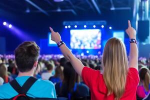 Excited audience at a large event, pointing at the stage photo