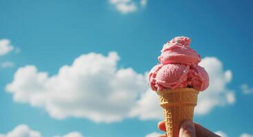 A person holding a pink ice cream cone in front of a blue sky photo