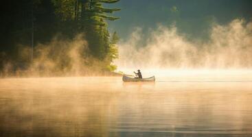 A man in a canoe on a lake with mist photo